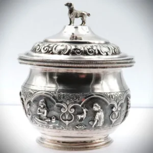 Runde Deckeldose aus 900er Silber mit aufgesetzter Hundefigur, umlaufenden Motiven und vergoldetem Innenraum, ca. 1930