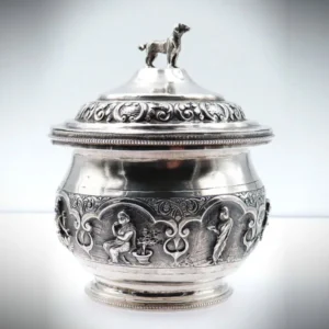 Vorderansicht der antiken Deckeldose aus 900er Silber mit figürlicher Darstellung und Hund auf dem ornamental verzierten Deckel