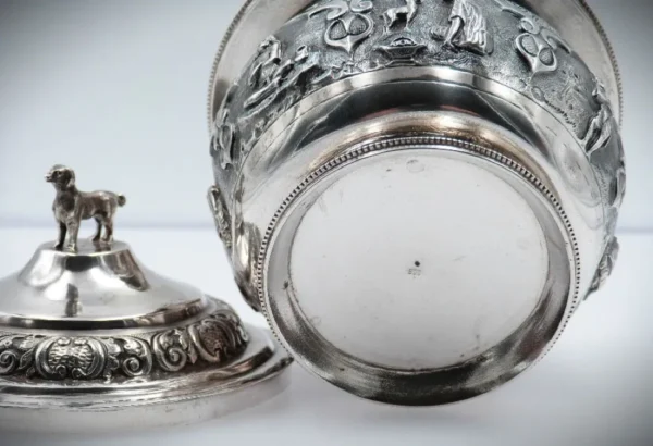 Deckeldose aus 900er Silber mit Hundefigur auf dem Deckel und detailreichen Reliefmotiven; Ansicht der Unterseite mit Silberstempel